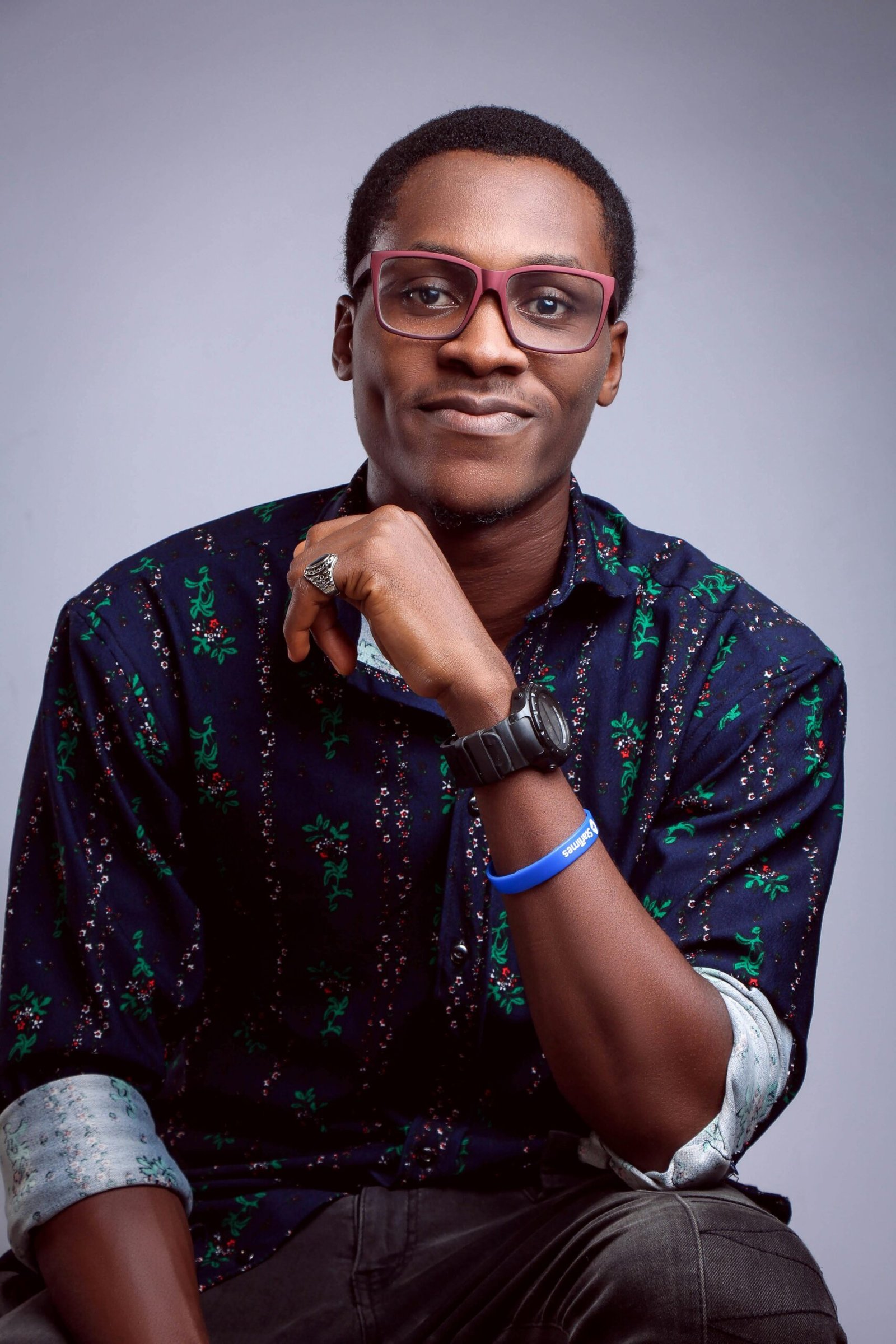 Charming young man in eyeglasses posing confidently with a smile against a purple background.